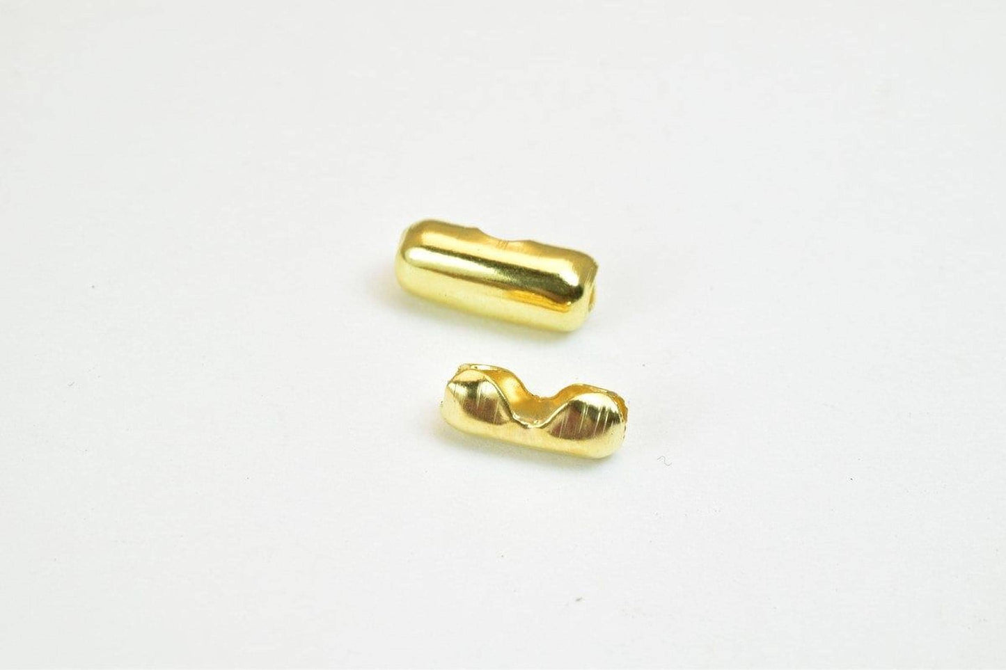 two small, shiny gold-colored objects on a plain white background.