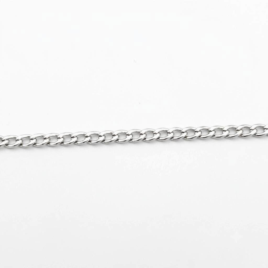 3mm silver curb chain in their open palm to demonstrate real-life scale and drape.