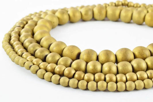 "Strands of round brass beads in varying sizes on white background"