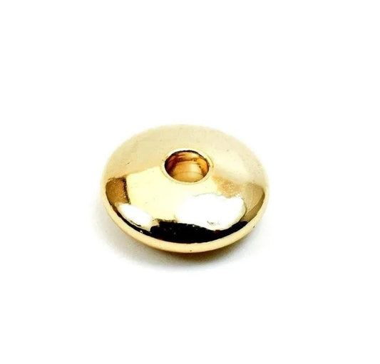 A shiny, golden-colored object with a small hole in the center, sitting on a white background.