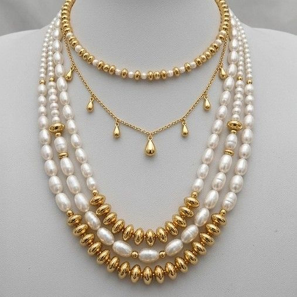 A gold and white pearl necklace with multiple strands of pearls and beads.