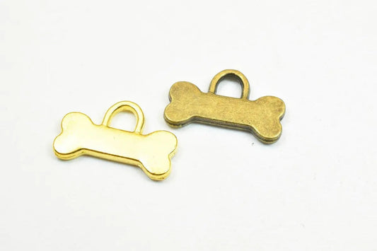 Brass dog bone charms on white background.