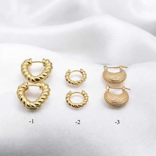 Gold hoop earrings set on white fabric, three styles with textured and twisted designs.