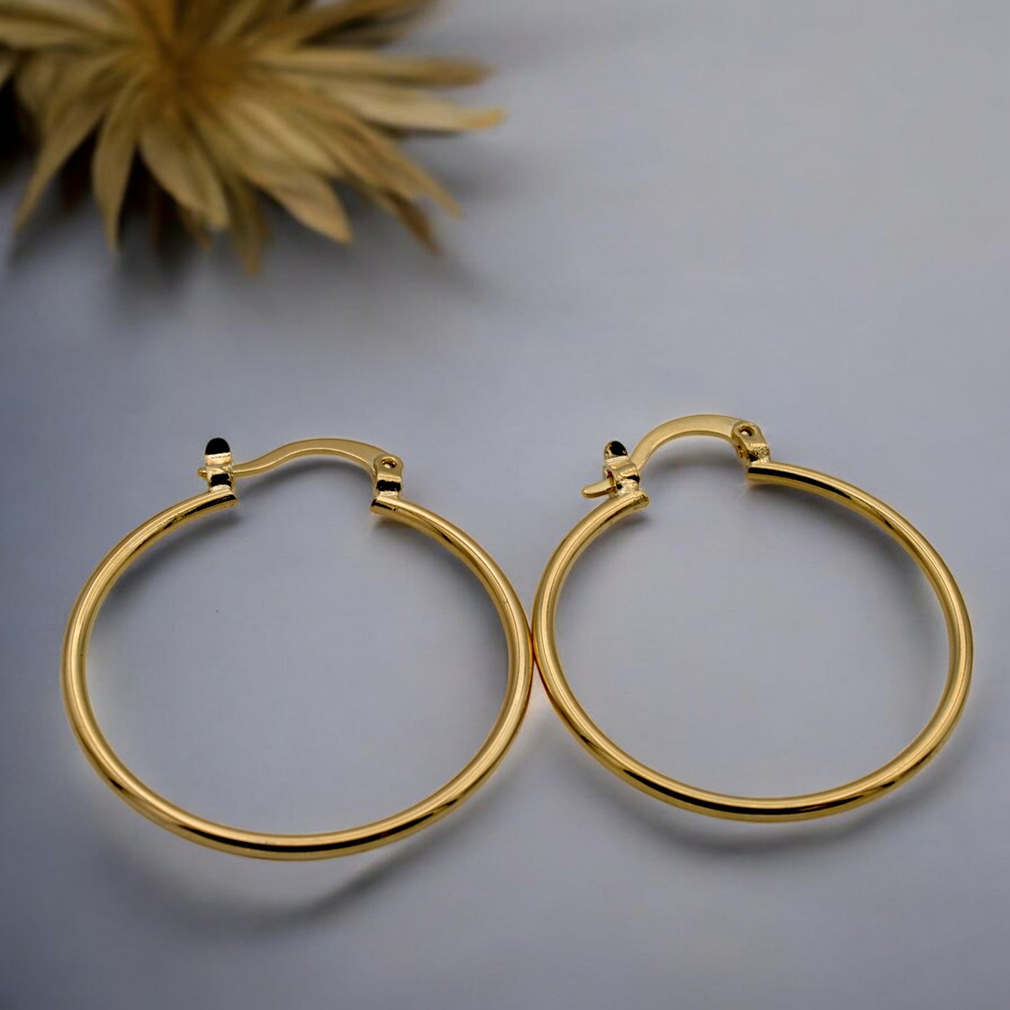 Display of gold hoop earrings in various sizes arranged on a stand, showcasing their sleek and polished finish.