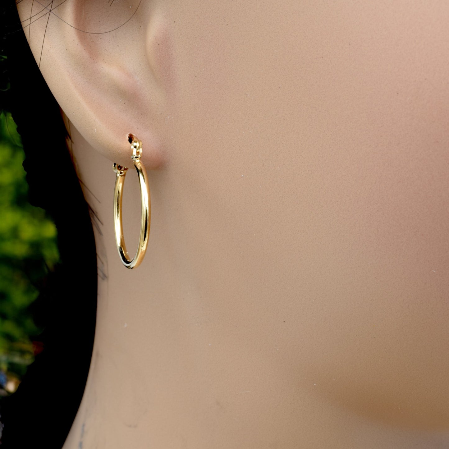 Display of gold hoop earrings in various sizes arranged on a stand, showcasing their sleek and polished finish.
