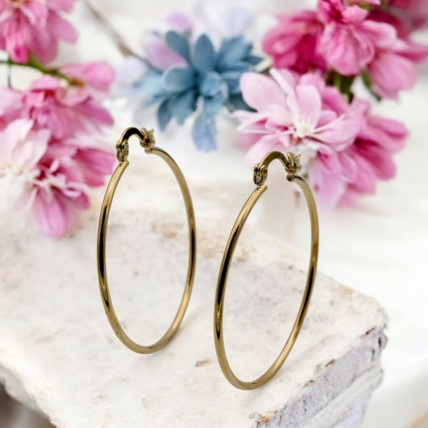 Display of gold hoop earrings in various sizes arranged on a stand, showcasing their sleek and polished finish.