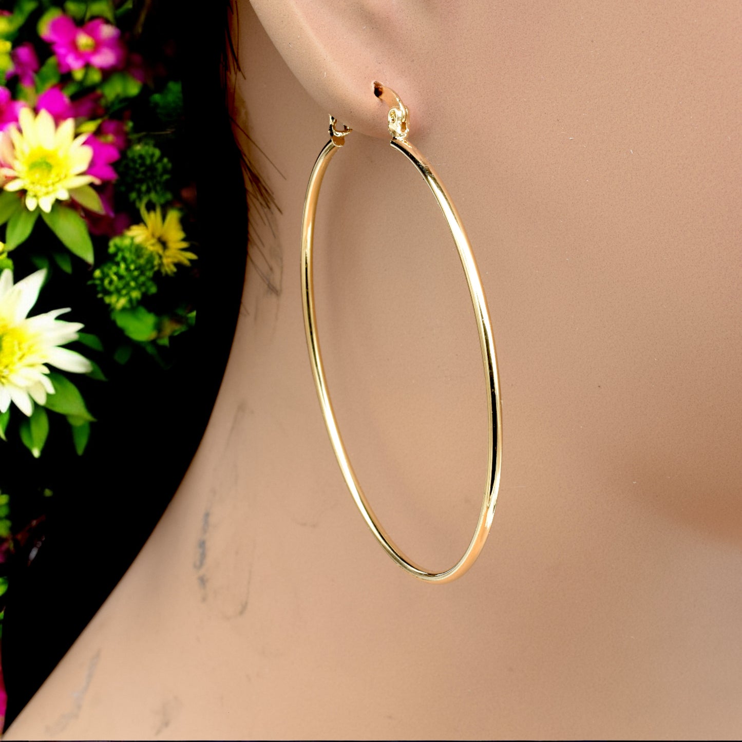Display of gold hoop earrings in various sizes arranged on a stand, showcasing their sleek and polished finish.