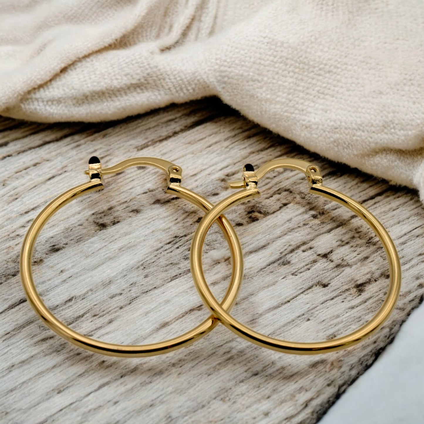 Display of gold hoop earrings in various sizes arranged on a stand, showcasing their sleek and polished finish.