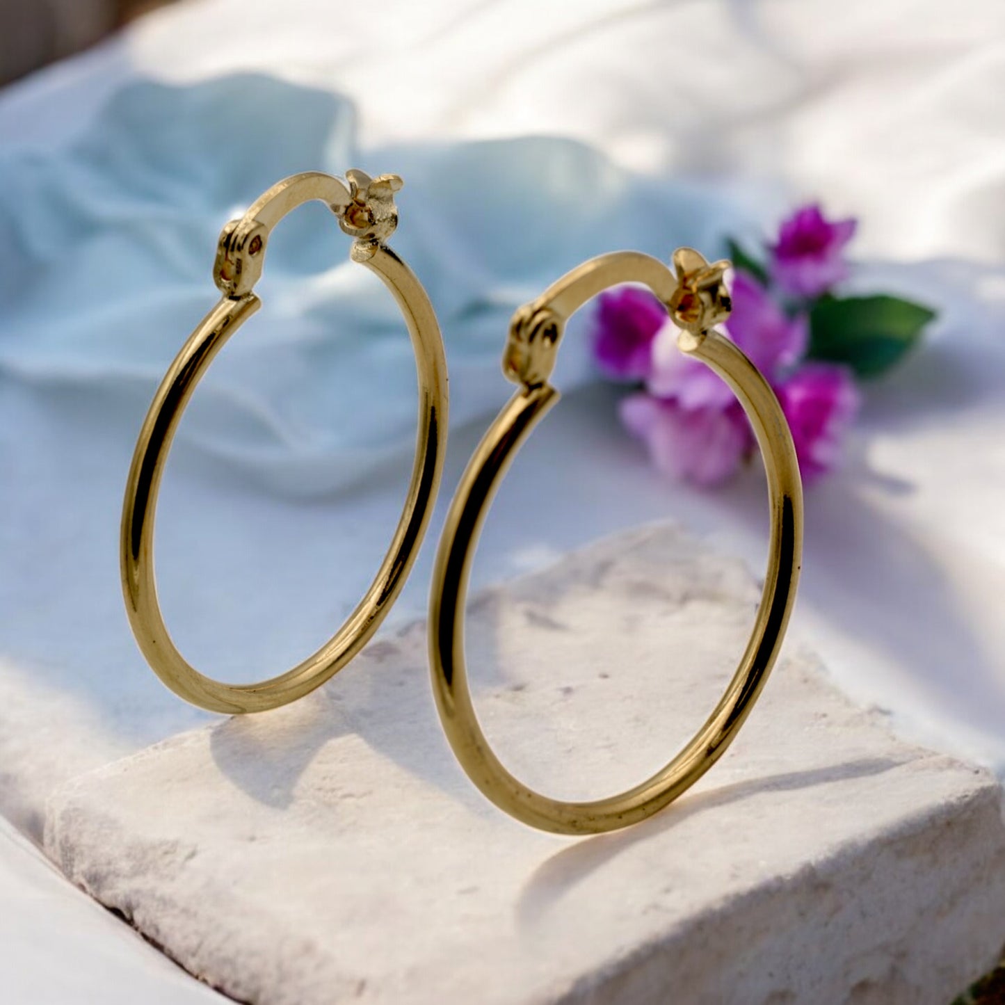 Display of gold hoop earrings in various sizes arranged on a stand, showcasing their sleek and polished finish.