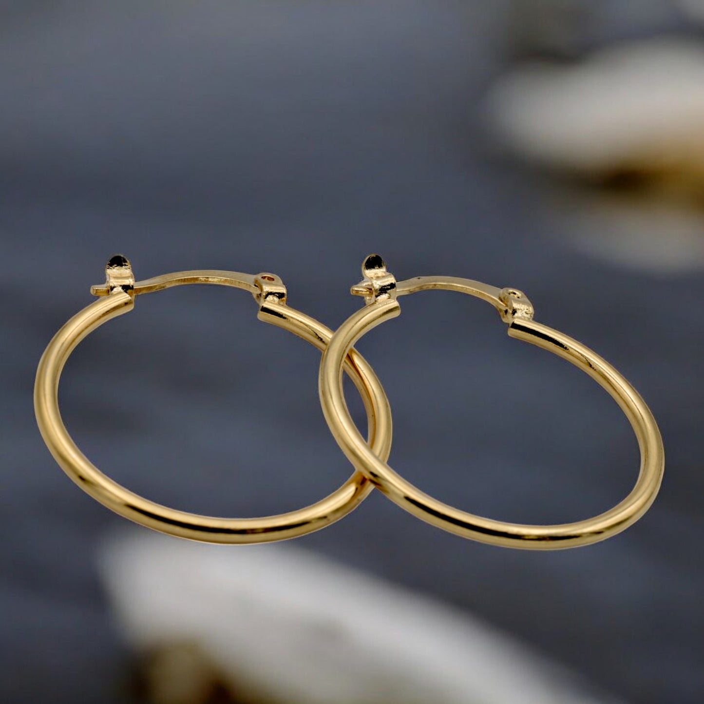 Display of gold hoop earrings in various sizes arranged on a stand, showcasing their sleek and polished finish.