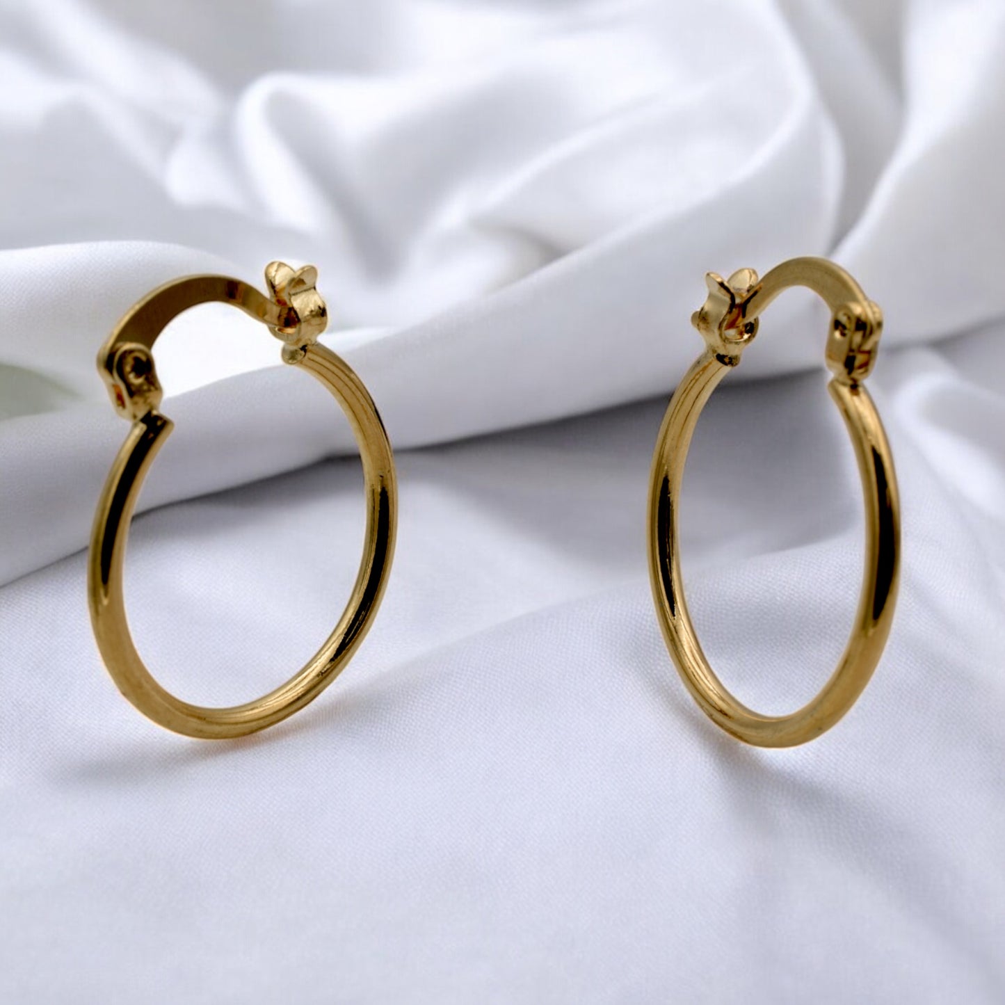 Display of gold hoop earrings in various sizes arranged on a stand, showcasing their sleek and polished finish.