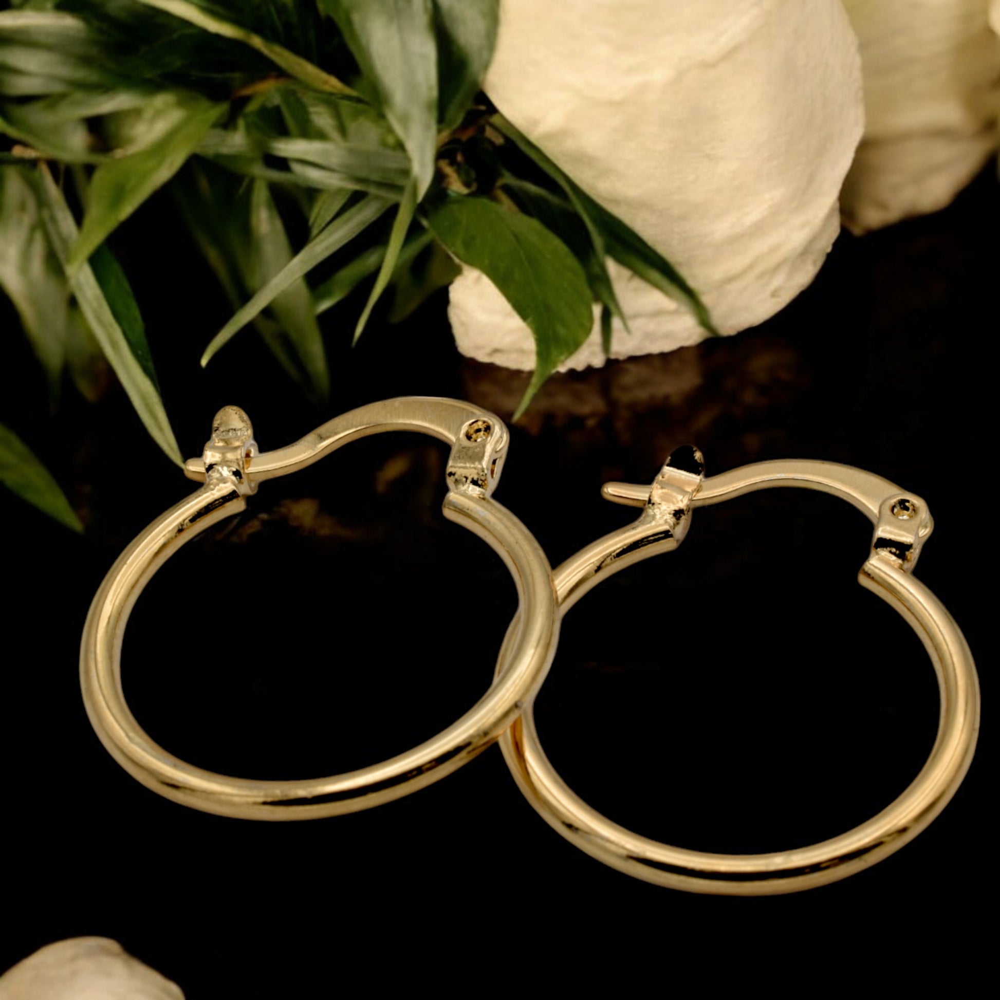 Display of gold hoop earrings in various sizes arranged on a stand, showcasing their sleek and polished finish.