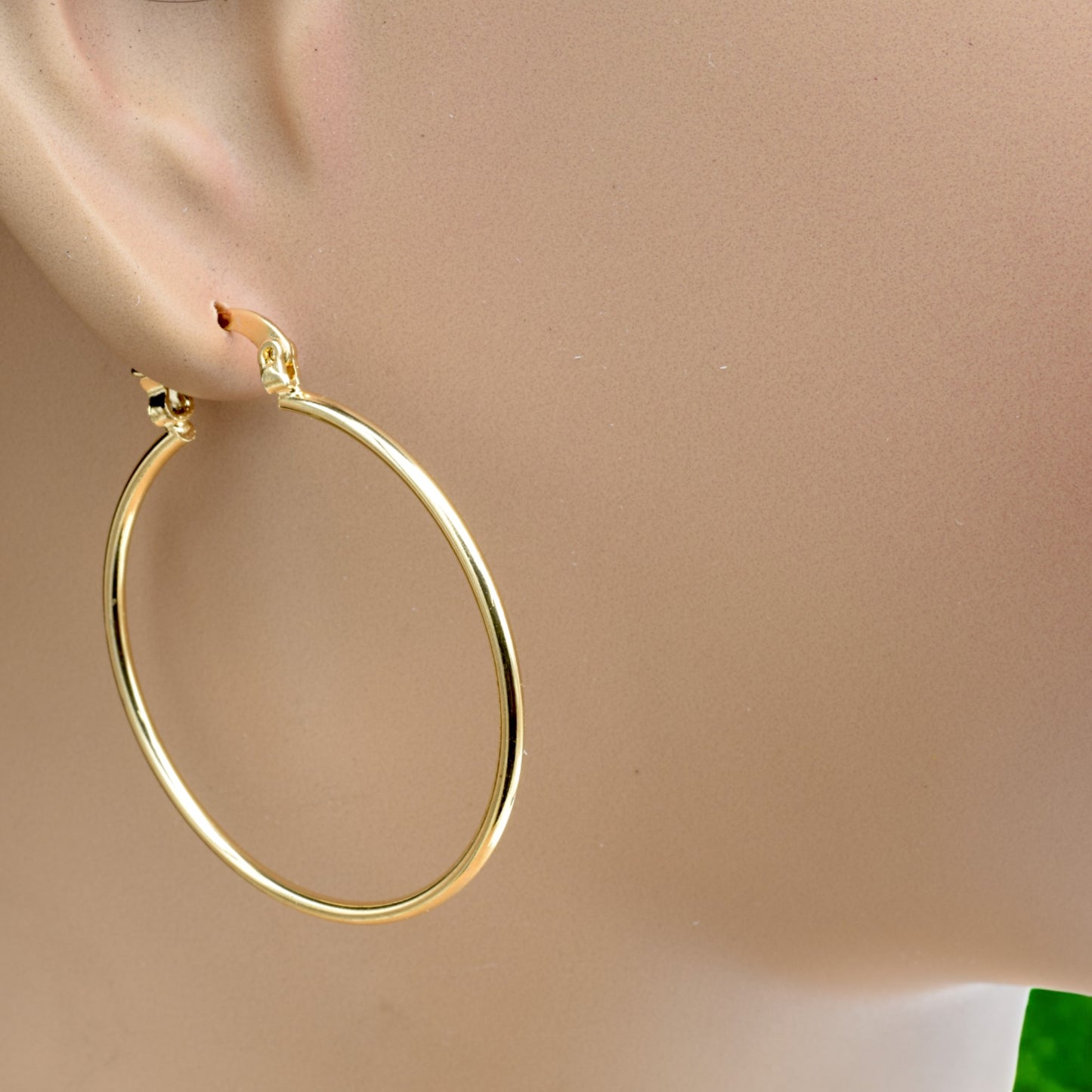 Display of gold hoop earrings in various sizes arranged on a stand, showcasing their sleek and polished finish.
