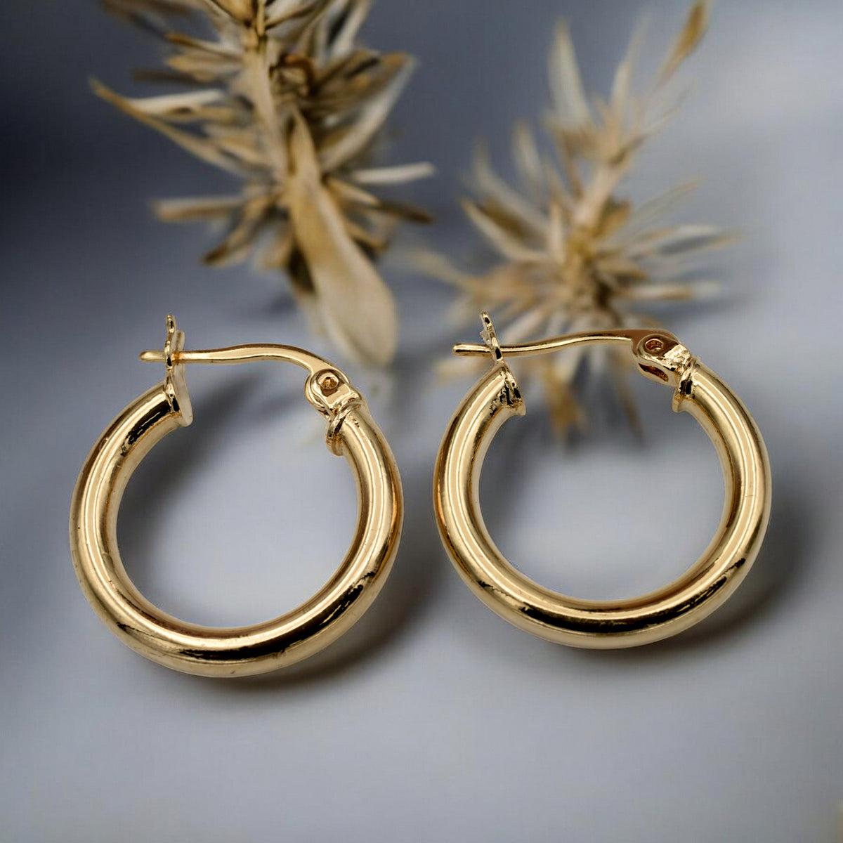 Set of gold hoop earrings in multiple sizes displayed on a black background, emphasizing their shiny, reflective surface and classic design.
