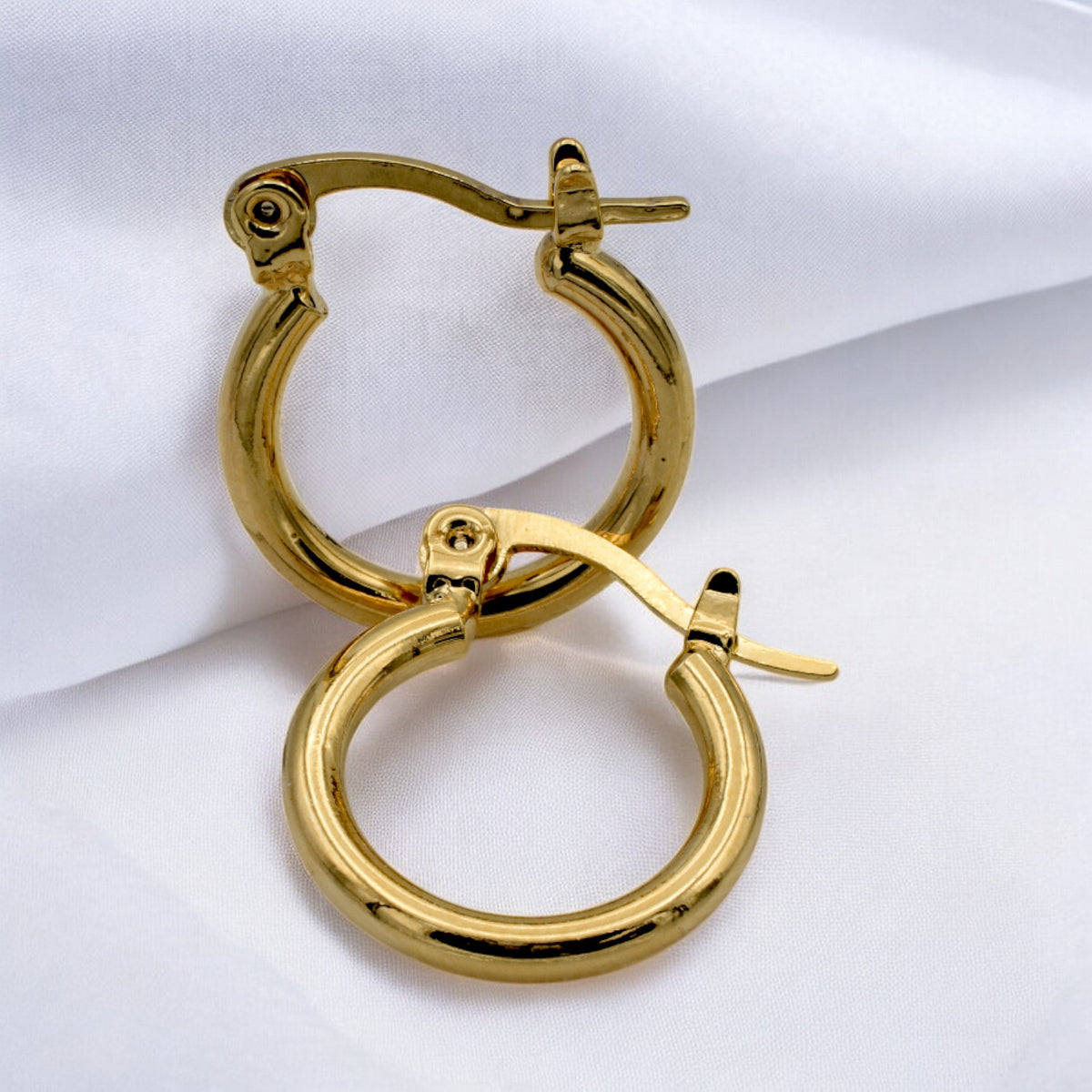 Set of gold hoop earrings in multiple sizes displayed on a black background, emphasizing their shiny, reflective surface and classic design.