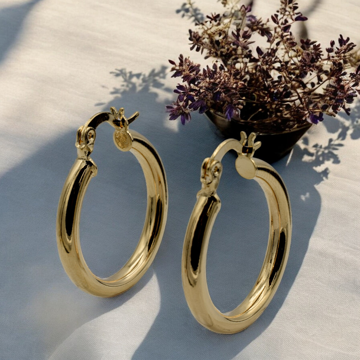 Set of gold hoop earrings in multiple sizes displayed on a black background, emphasizing their shiny, reflective surface and classic design.