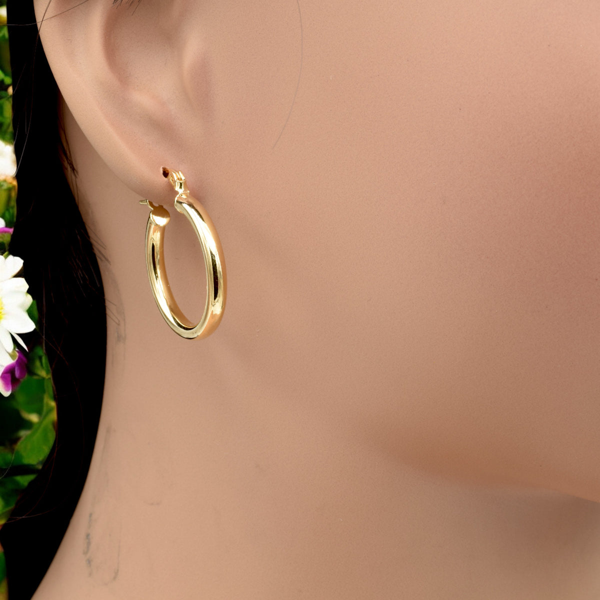 Set of gold hoop earrings in multiple sizes displayed on a black background, emphasizing their shiny, reflective surface and classic design.