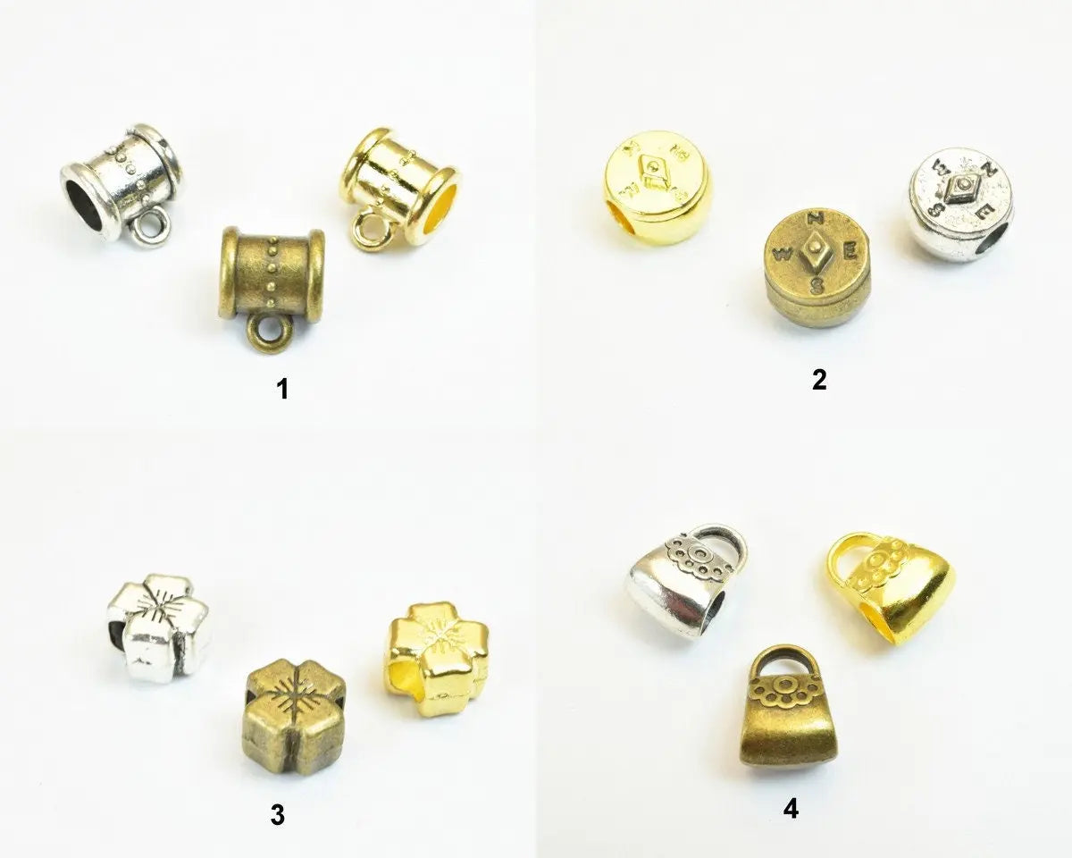 Assorted metal bead charms in silver, gold, and bronze finishes, featuring barrel, compass, floral, and bag designs.