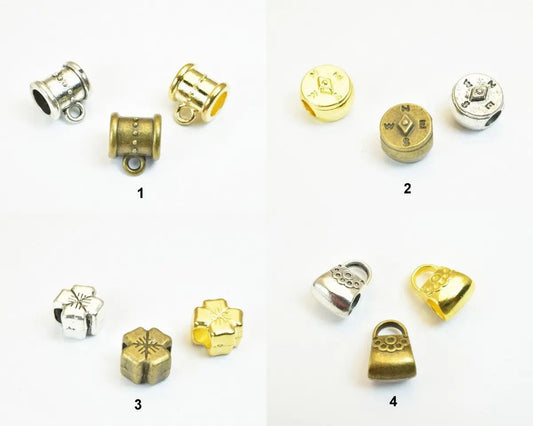 Assorted metal bead charms in silver, gold, and bronze finishes, featuring barrel, compass, floral, and bag designs.