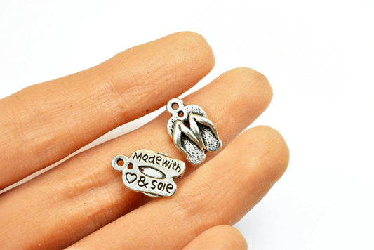 "Miniature flip flop and tag charms, held in hand, etched with 'Made with Sole'"