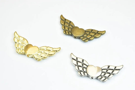 Gold, silver, and bronze heart-shaped winged pendants on white background.