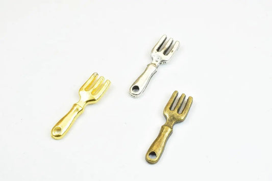 Three miniature metal fork charms in gold, silver, and bronze on a white background.
