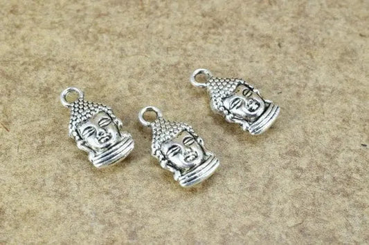 Silver Buddha head charms on a textured beige background.