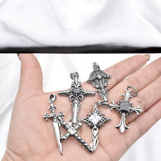 Hand holding five silver cross sword pendants with black gemstones.