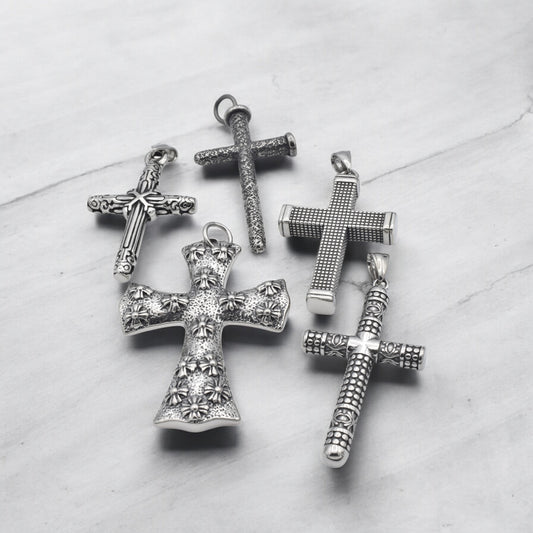 Vintage silver cross pendants with intricate designs on marble background.