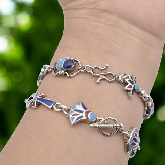 Silver and blue gemstone bracelet with unique charms on wrist.