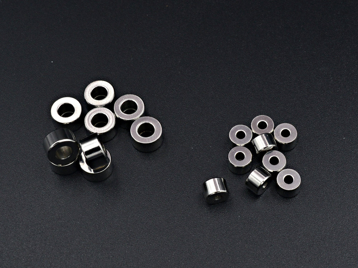 May include: A group of silver metal rings, some stacked on top of each other, and some scattered on a black surface.
Primer plano de cuentas rondel lisas de acero inoxidable para hacer joyas