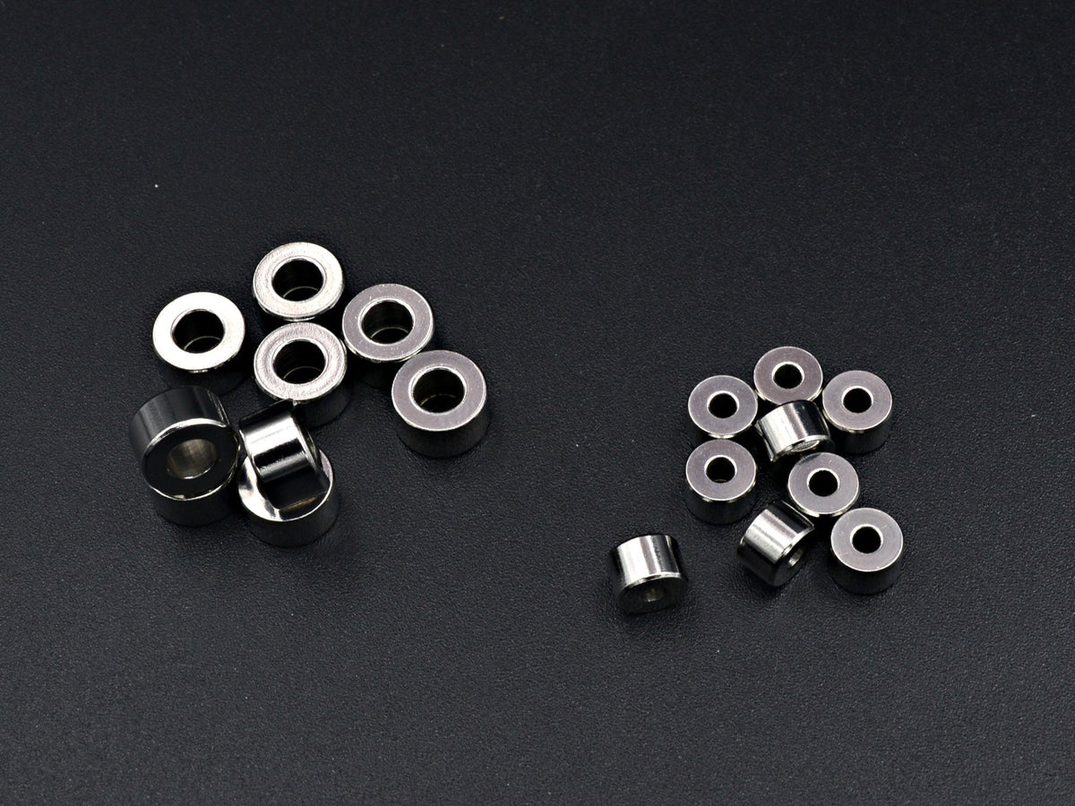 May include: A group of silver metal rings, some stacked on top of each other, and some scattered on a black surface.
Primer plano de cuentas rondel lisas de acero inoxidable para hacer joyas