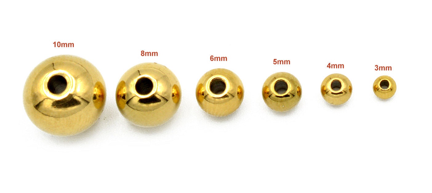 Macro shot of polished gold-plated stainless steel beads showing smooth seamless finish