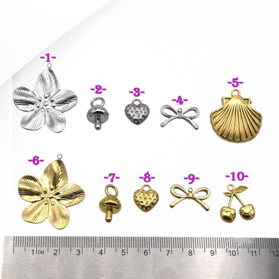 Collection of various metal pendants with a ruler for scale on a white background