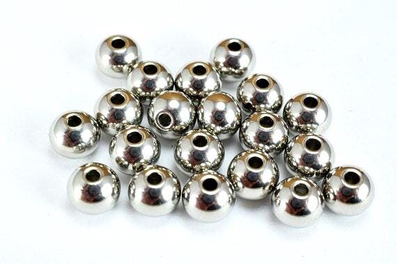 Pile of tarnish-resistant stainless steel beads with uniform round shape and drilled holes