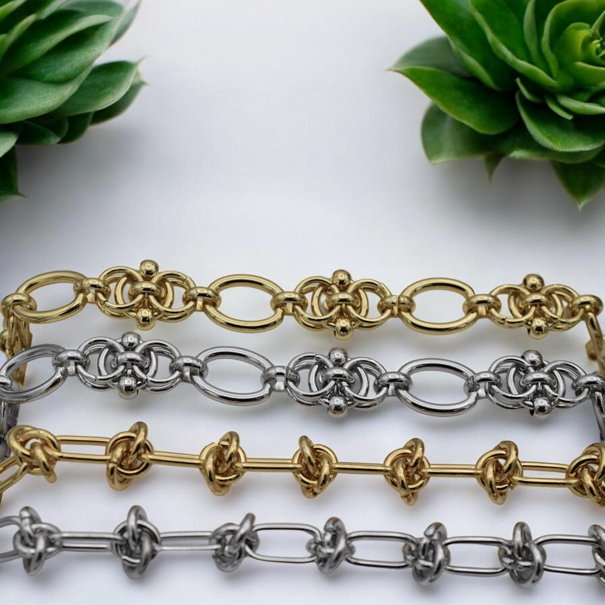 Close-up of gold chain with double-knot accents and smooth oval links, highlighting craftsmanship and shine.