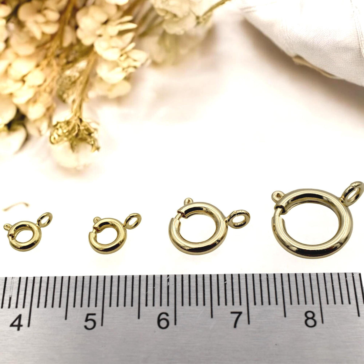 Single gold-filled round clasp resting on a marble background, ideal for necklaces and bracelets.