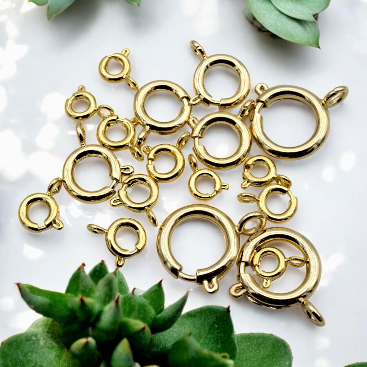 Gold-filled round clasp in use on a handmade bracelet, photographed on a textured background with dried flowers.