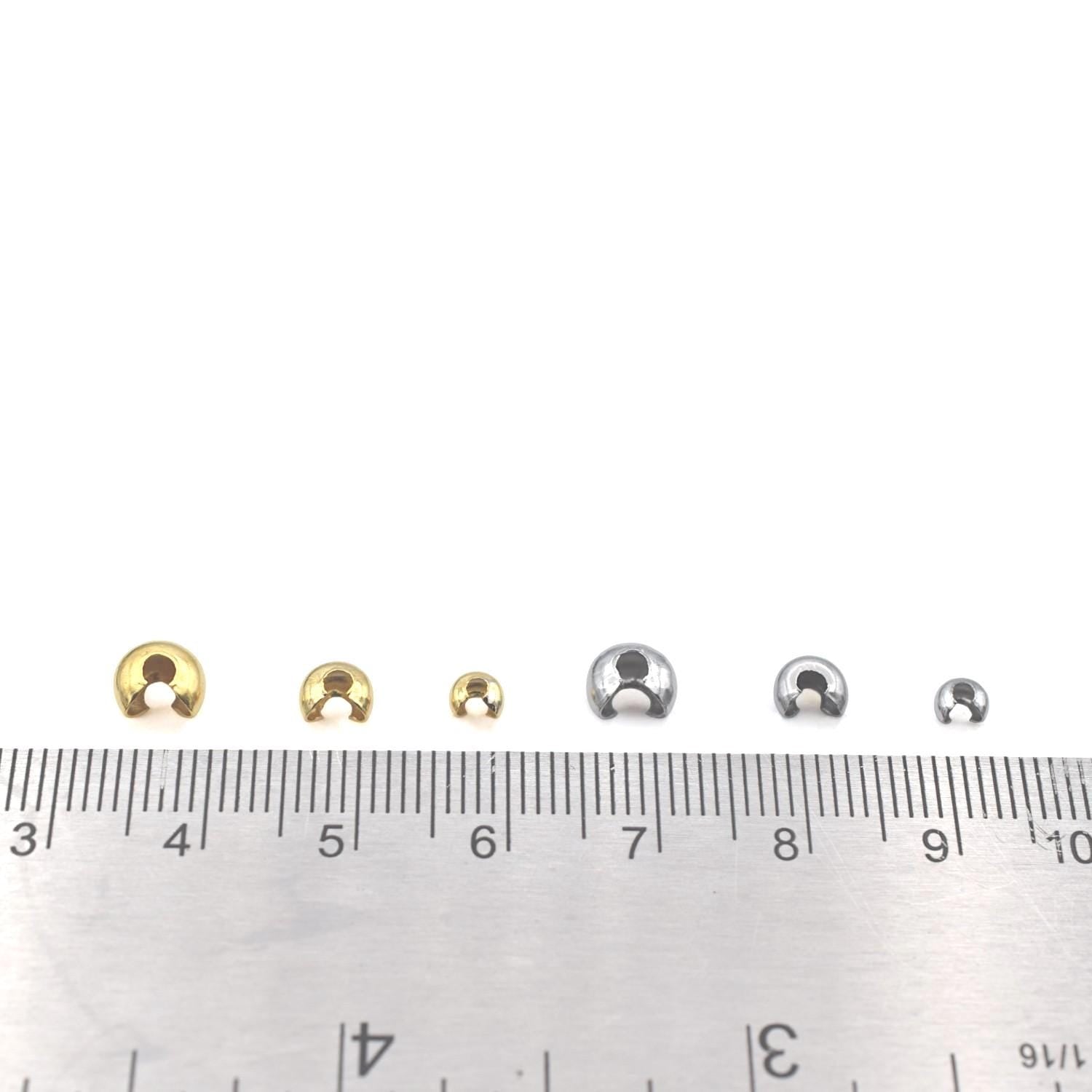 Single gold bead cover held by pliers, demonstrating how to close it over a knot for a clean jewelry finish.