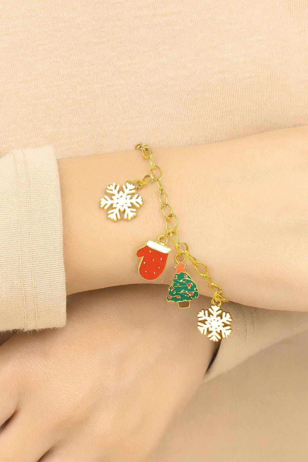 a woman wearing a bracelet with the Christmas charms (red mitten, green trees, and snowflakes) hanging beautifully from a gold-tone chain.