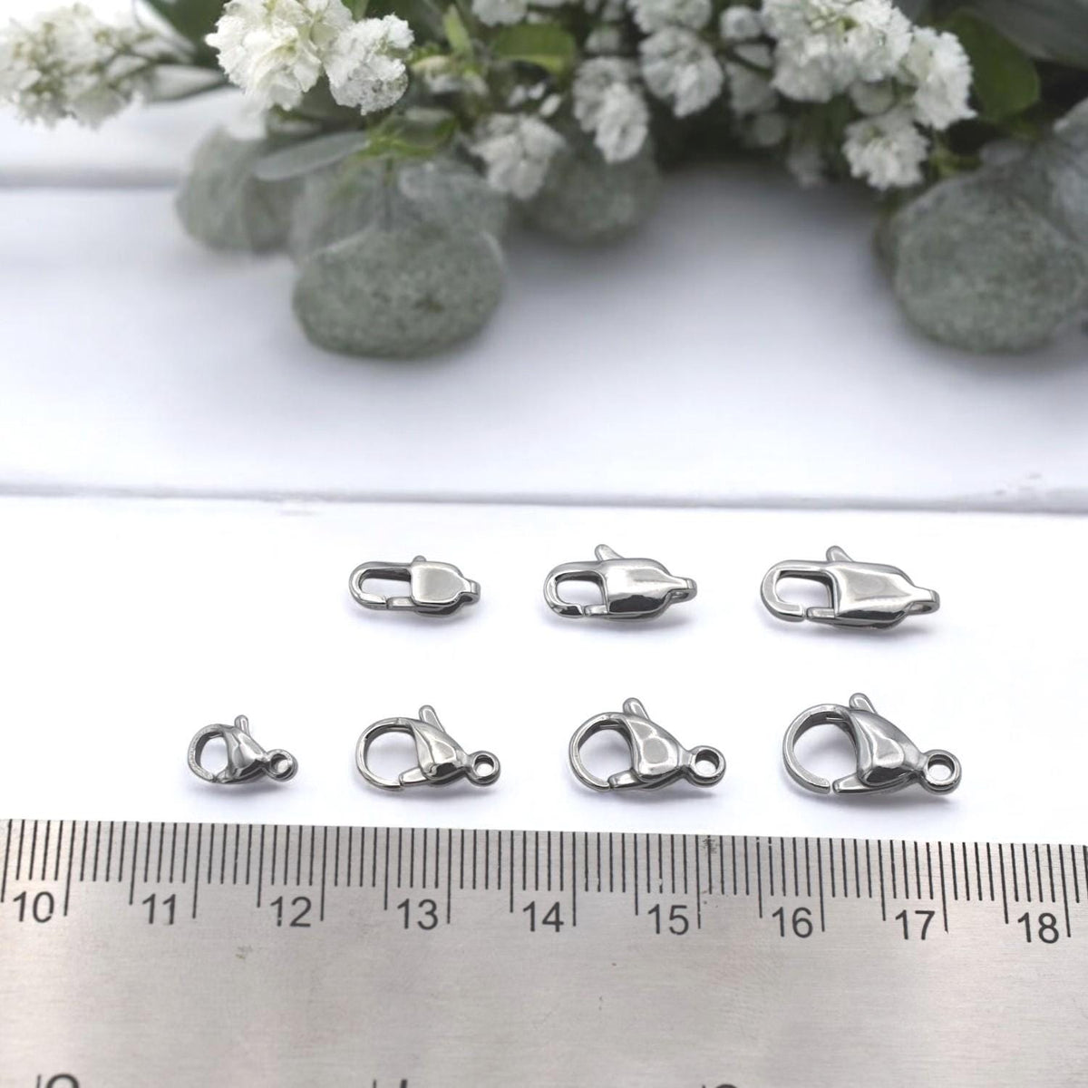 Lobster clasp with jump ring shown next to ruler for precise size reference.