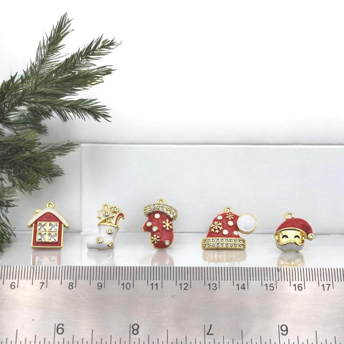 Christmas jewelry charms including stocking with gold stars, mitten with snowflakes, and rhinestone Santa hat.