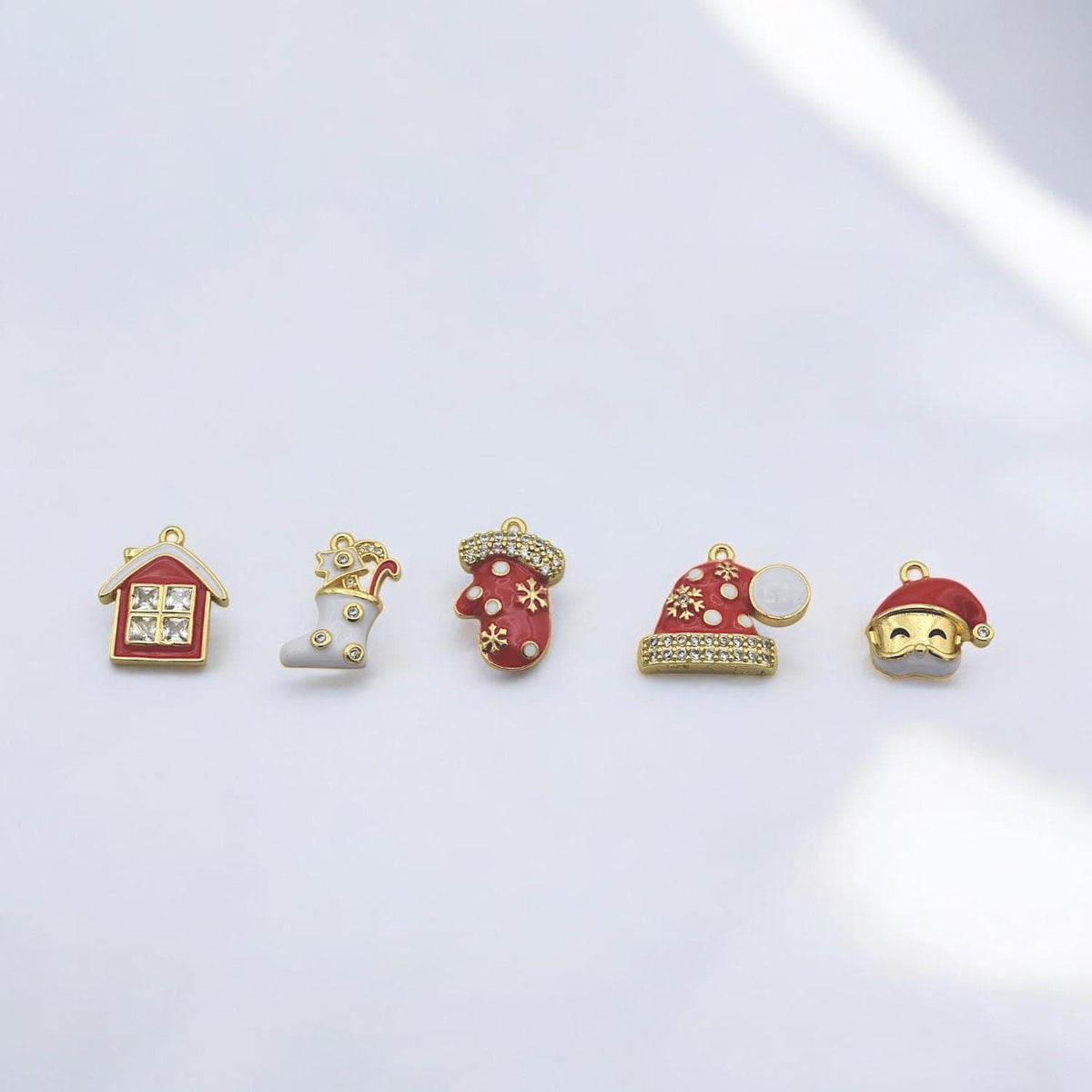 Five decorative charms for holiday crafts: stocking, house, mitten, and two Santa hats with festive sparkle