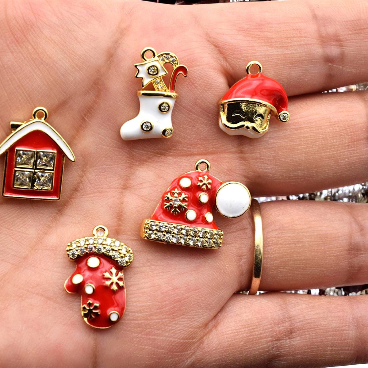 Detailed enamel charms shaped like stocking, mitten, house, and Santa hats with snowflake and rhinestone designs.