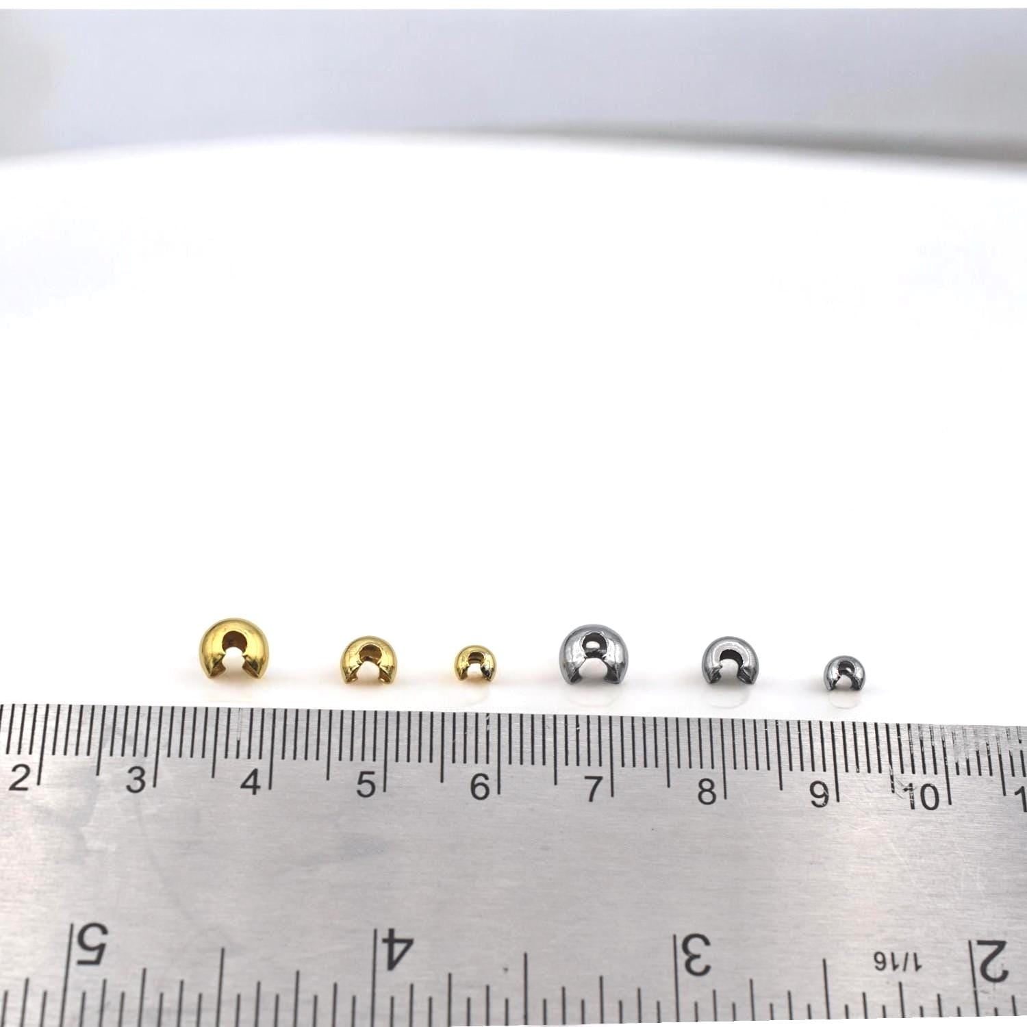 Assorted gold knot covers arranged in a row, showing size variations for hiding crimps and knots in bracelets and necklaces.