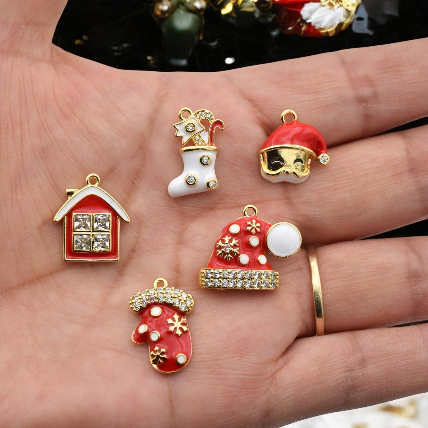 Close-up of five Christmas-themed charms including Santa hats, stocking, mitten, and rhinestone-decorated house.