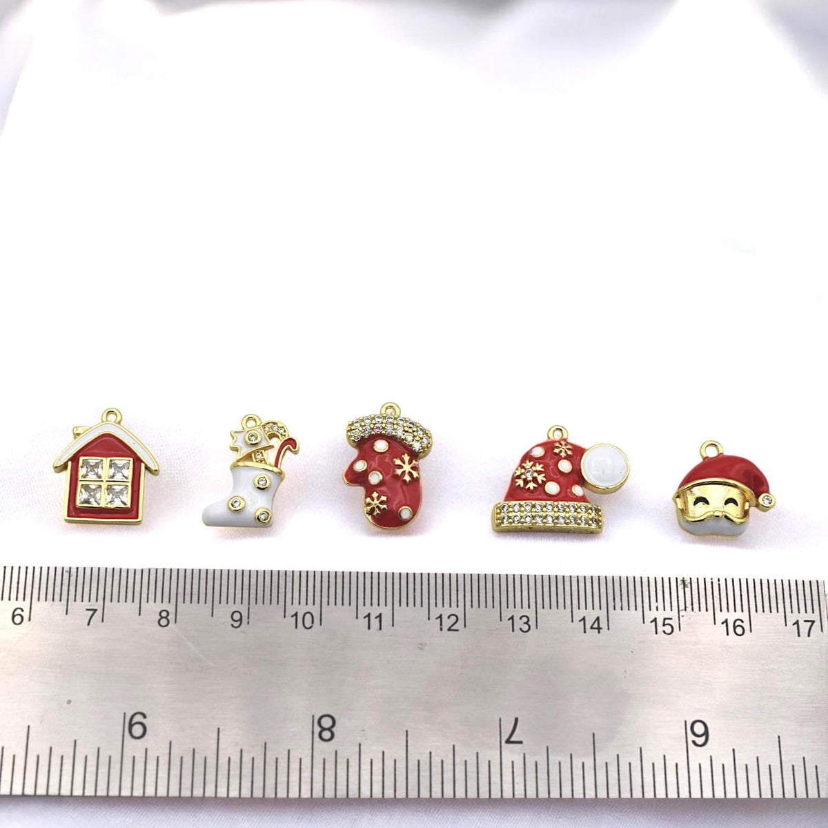 Holiday bead charms in red, white, and gold designs with snowflakes, stars, and rhinestone accents.