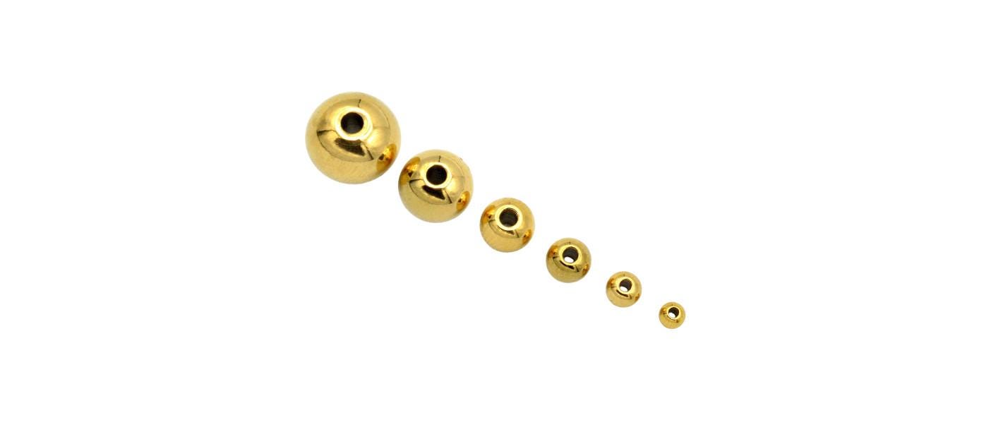 Assorted gold-plated spacer beads organized by size in small containers for crafting