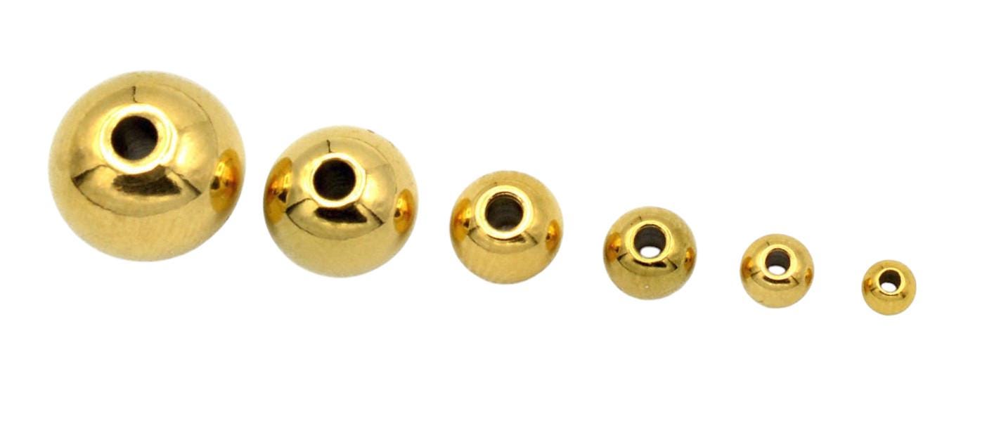 Close-up of gold-plated stainless steel seamless spacer beads in assorted sizes on a white background