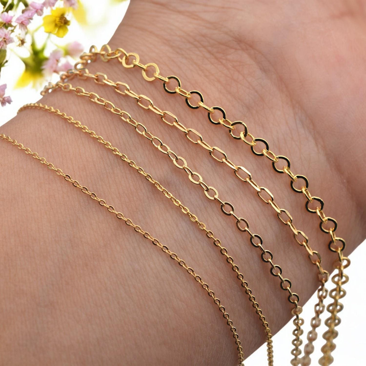 Close-up of wrist wearing layered gold filled cable link chain bracelets